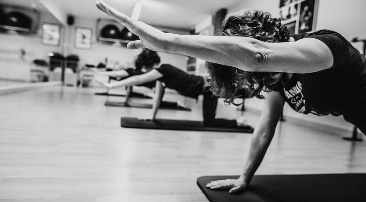 Clase de Pilates en suelo en Alameda Studio (Santander): alumnos en cuadrupedia sobre colchonetas, elevando un brazo y una pierna para trabajar estabilidad y control.