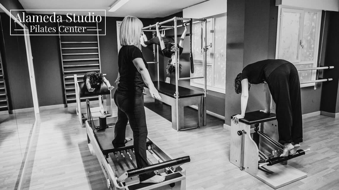 Clase de Pilates con aparatos en Alameda Studio (Santander), con una instructora supervisando a dos alumnas en Reformer y Chair.